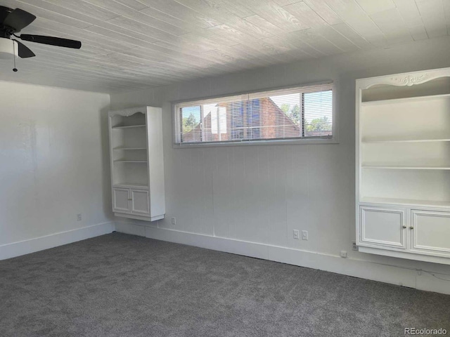 empty room with ceiling fan, dark carpet, and wood ceiling