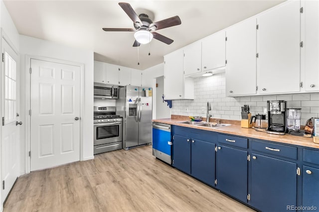 3118 E San Miguel St, Colorado Springs, CO 80909 - kitchen featuring appliances with stainless steel finishes, a sink, blue cabinets, a ceiling fan, and light wood-style flooring