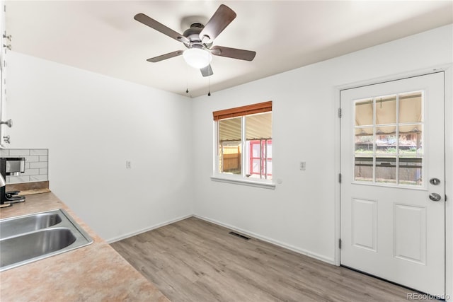 3118 E San Miguel St, Colorado Springs, CO 80909 - kitchen with light wood-style floors, a ceiling fan, light countertops, backsplash, and baseboards