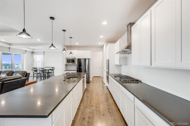 5651 Gore Creek Pl, Brighton, CO 80601 - kitchen with appliances with stainless steel finishes, wall chimney range hood, dark countertops, light wood-type flooring, and recessed lighting