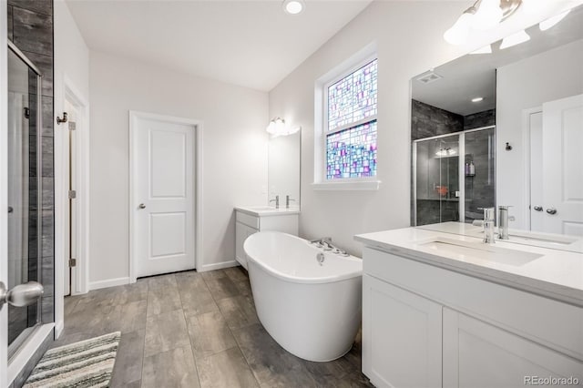 5651 Gore Creek Pl, Brighton, CO 80601 - bathroom featuring a stall shower, two vanities, a freestanding tub, and wood finished floors