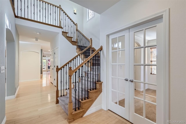 staircase featuring a wealth of natural light, french doors, baseboards, and wood finished floors