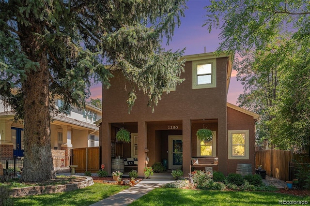 view of front of house featuring a yard, fence, and stucco siding