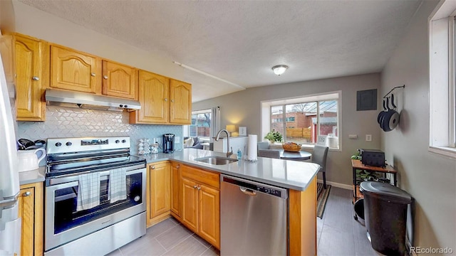 kitchen with appliances with stainless steel finishes, light tile patterned flooring, tasteful backsplash, kitchen peninsula, and sink