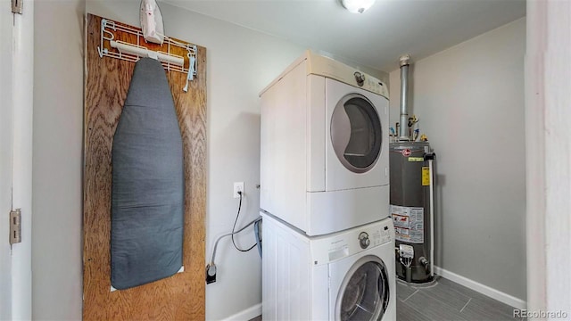 28 W Broadmoor Dr, Littleton, CO 80120 - laundry area featuring stacked washing maching and dryer, gas water heater, baseboards, tile patterned flooring, and laundry area
