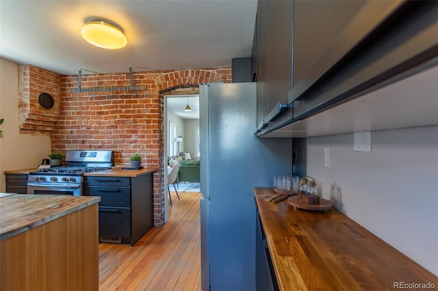 604 W 1st St, Salida, CO 81201 - kitchen with butcher block countertops, stainless steel appliances, light wood-style flooring, blue cabinets, and brick wall