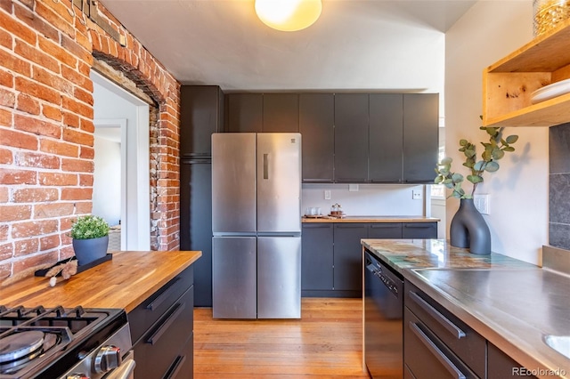 604 W 1st St, Salida, CO 81201 - kitchen featuring freestanding refrigerator, dishwashing machine, light wood-style floors, stainless steel countertops, and brick wall