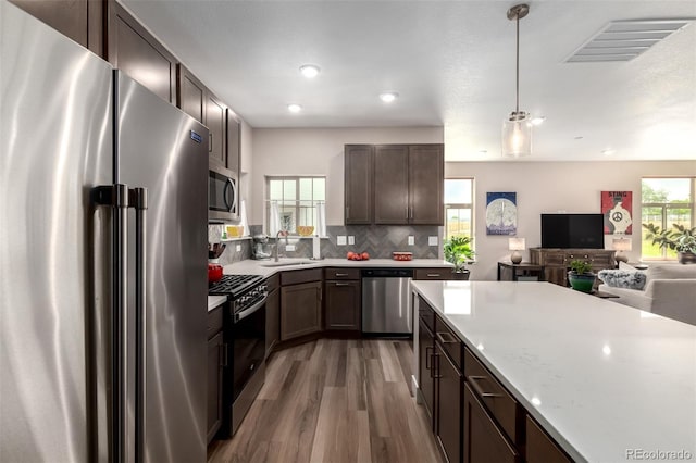 12673 Tamarac St, Thornton, CO 80602 - kitchen featuring appliances with stainless steel finishes, light wood-style floors, light countertops, open floor plan, and dark brown cabinetry