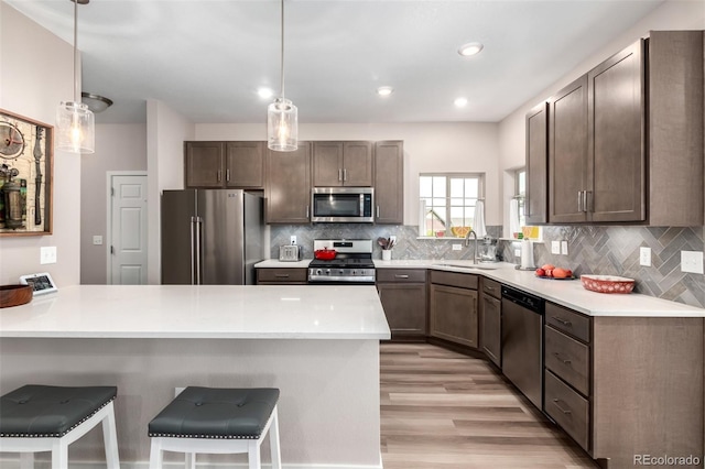 12673 Tamarac St, Thornton, CO 80602 - kitchen with stainless steel appliances, a peninsula, a breakfast bar area, light wood-style floors, and backsplash