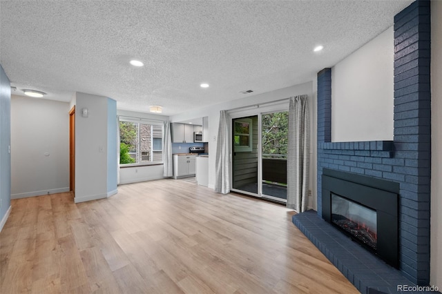 8378 S Upham Way Unit B205, Littleton, CO 80128 - unfurnished living room featuring a textured ceiling, a fireplace, light wood-style floors, baseboards, and recessed lighting