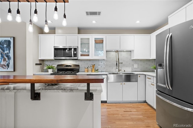 kitchen featuring visible vents, light wood-style flooring, white cabinetry, stainless steel appliances, and light countertops