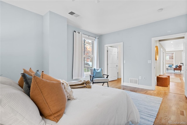 bedroom with light wood-style flooring, baseboards, and visible vents