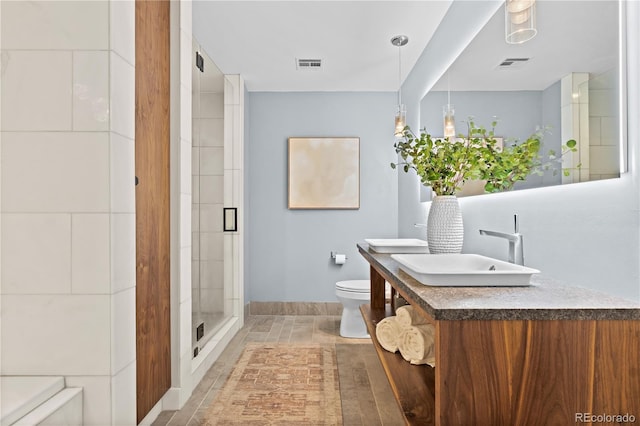 bathroom featuring visible vents, toilet, a stall shower, and vanity