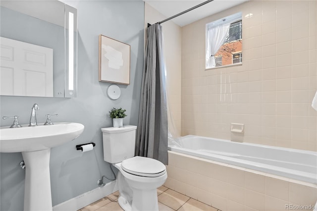 full bathroom with tile patterned flooring, baseboards, toilet, tiled shower / bath combo, and a sink