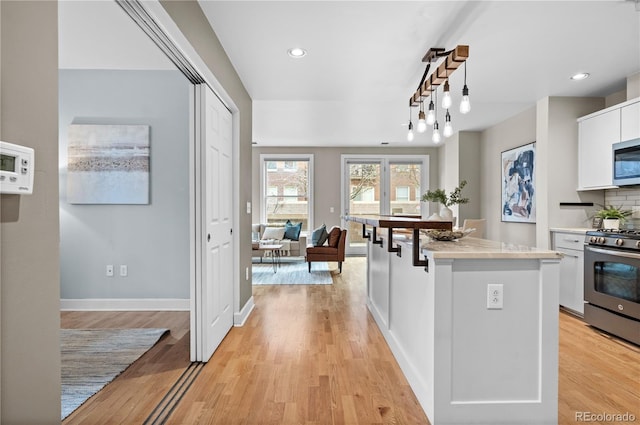 kitchen with light wood-style flooring, appliances with stainless steel finishes, and white cabinets