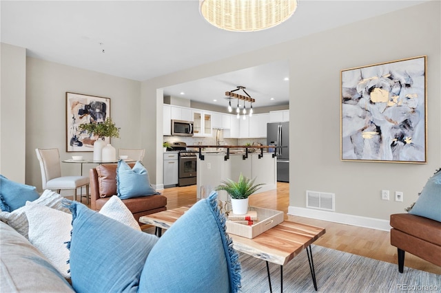 living area featuring recessed lighting, baseboards, visible vents, and light wood finished floors