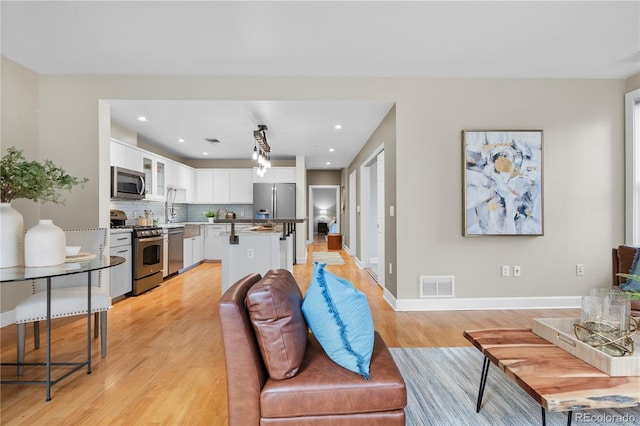 living room with recessed lighting, visible vents, baseboards, and light wood-style flooring