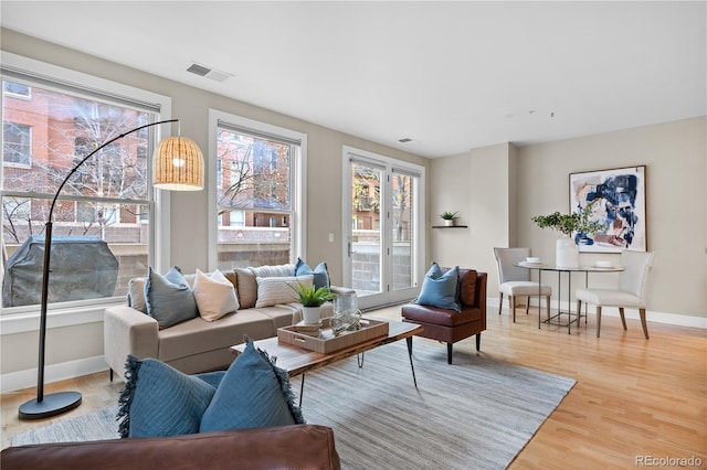 living area with light wood-style floors, visible vents, and baseboards