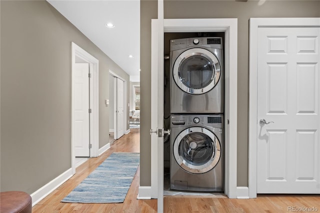 washroom featuring recessed lighting, light wood-style floors, stacked washer / drying machine, baseboards, and laundry area