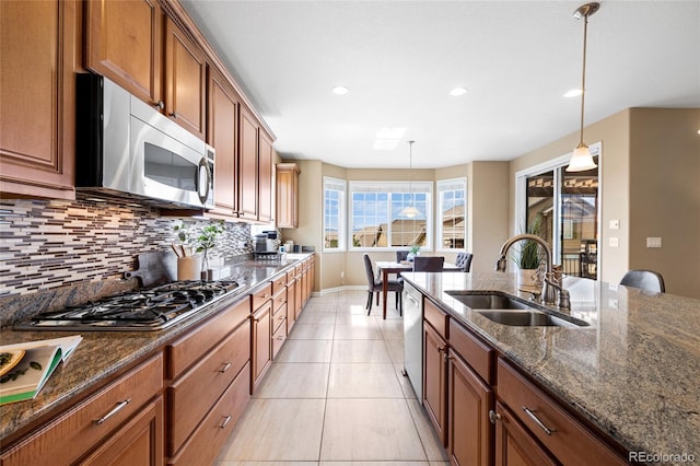 kitchen featuring tasteful backsplash, dark stone countertops, sink, hanging light fixtures, and appliances with stainless steel finishes