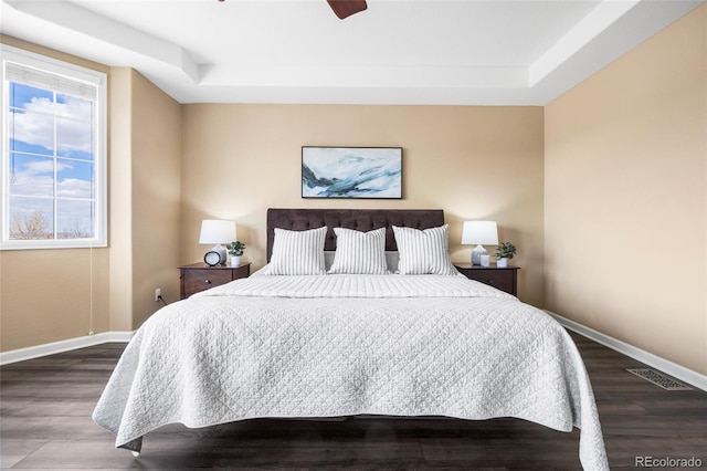 bedroom with ceiling fan, hardwood / wood-style flooring, and a tray ceiling