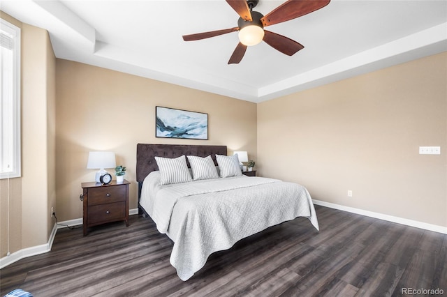 bedroom featuring ceiling fan, a tray ceiling, and dark hardwood / wood-style floors