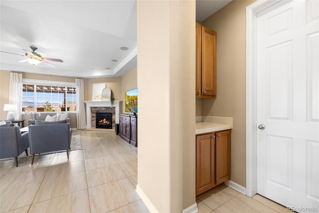 interior space with ceiling fan and a stone fireplace