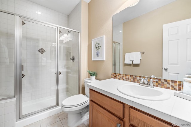 bathroom with toilet, vanity, tile patterned floors, decorative backsplash, and an enclosed shower