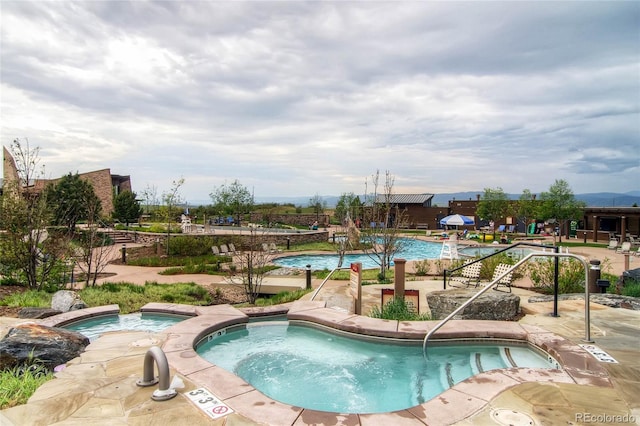 view of pool with a hot tub and a patio area