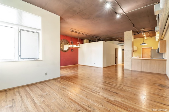 unfurnished room with track lighting and light hardwood / wood-style floors