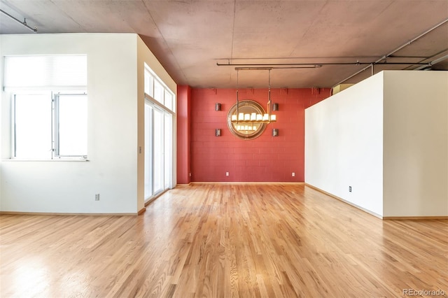 spare room featuring a notable chandelier and hardwood / wood-style flooring