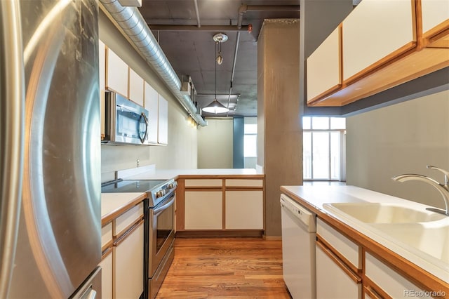 kitchen with white cabinetry, appliances with stainless steel finishes, sink, and light wood-type flooring