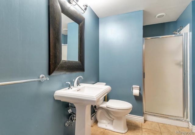 bathroom featuring tile patterned flooring, a shower with shower door, and toilet