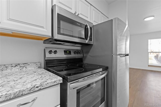 kitchen featuring white cabinets, light stone counters, stainless steel appliances, and light hardwood / wood-style flooring