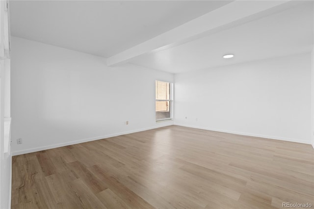 empty room featuring beam ceiling and light hardwood / wood-style floors