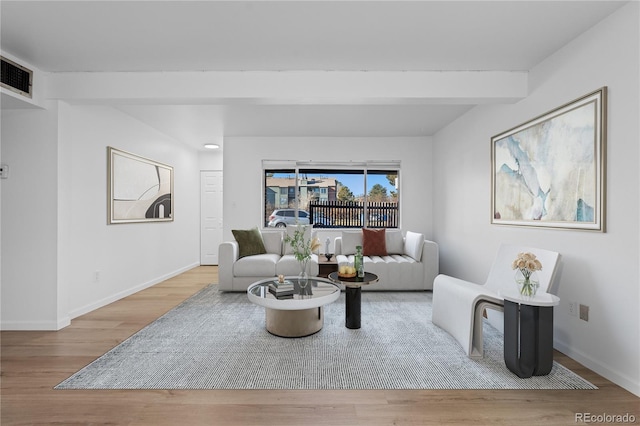 living area with beam ceiling, visible vents, baseboards, and wood finished floors