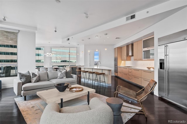 living area featuring baseboards, visible vents, a chandelier, and dark wood-style flooring