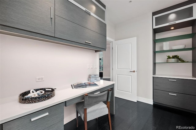 home office with dark wood-type flooring and baseboards