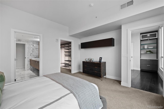 carpeted bedroom featuring baseboards, visible vents, ensuite bath, a spacious closet, and a closet