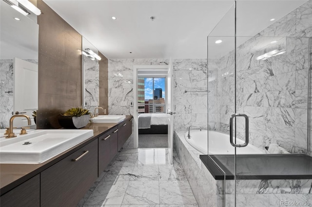 ensuite bathroom featuring stone wall, marble finish floor, and a sink