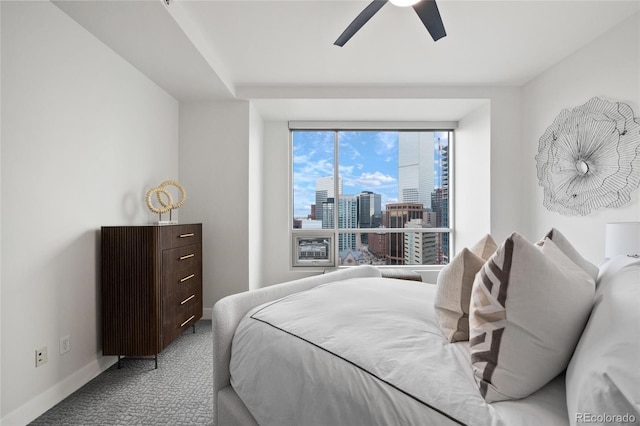 carpeted bedroom with a view of city, ceiling fan, and baseboards