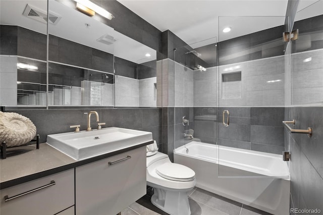 bathroom with tile walls, visible vents, toilet, enclosed tub / shower combo, and tile patterned flooring