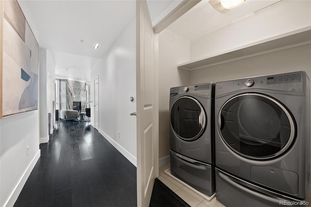 laundry room featuring laundry area, baseboards, washer and clothes dryer, and dark wood finished floors