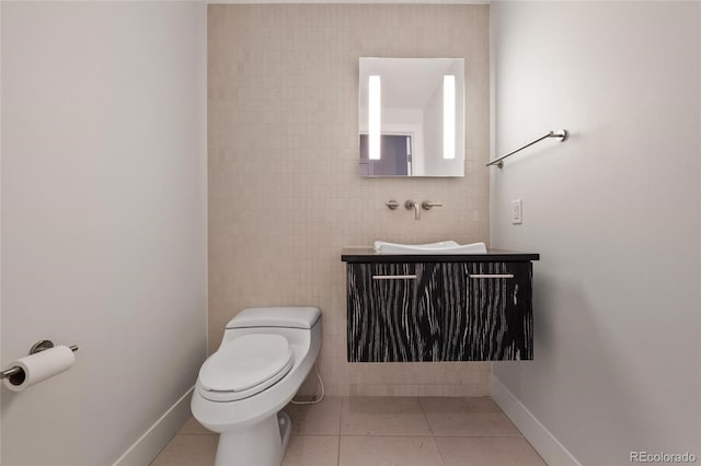 bathroom with tile patterned flooring, baseboards, vanity, and toilet