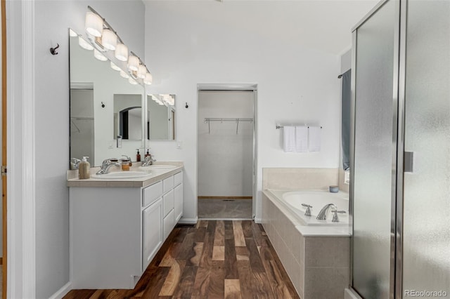 16257 E 105th Cir, Commerce City, CO 80022 - bathroom featuring wood finished floors, a walk in closet, a garden tub, double vanity, and a shower stall