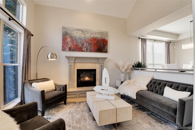 living room featuring an inviting chandelier, a tray ceiling, and a fireplace