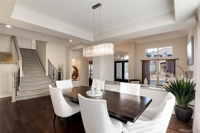 dining area with a tray ceiling, dark hardwood / wood-style floors, and a chandelier