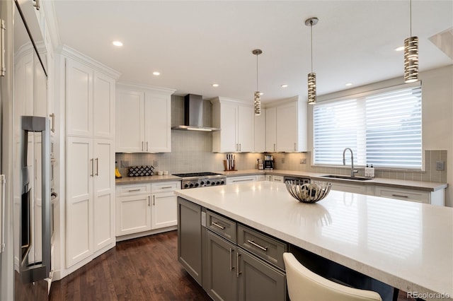 kitchen featuring wall chimney exhaust hood, sink, white cabinetry, decorative light fixtures, and decorative backsplash