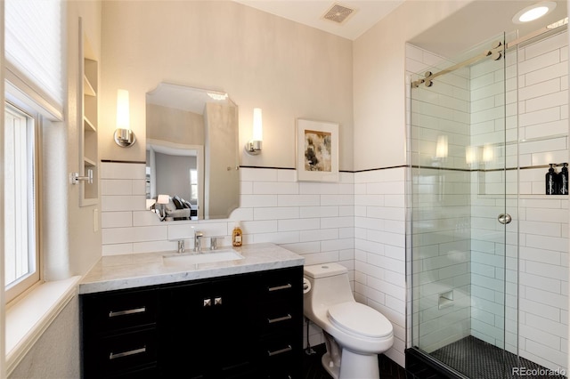 bathroom featuring vanity, toilet, a shower with shower door, and tile walls