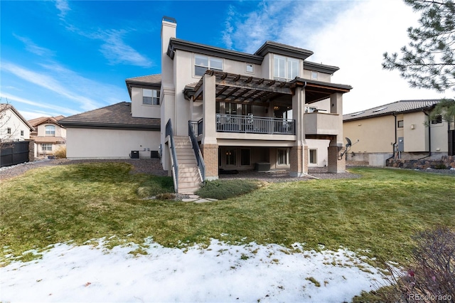 snow covered back of property featuring a balcony, a yard, and a pergola